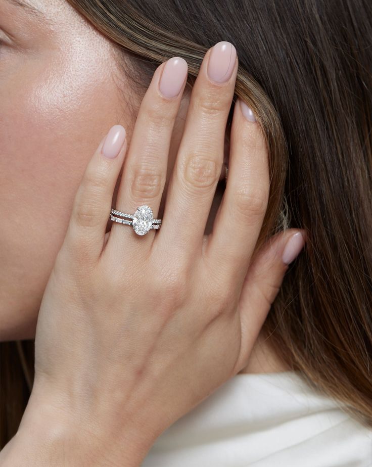 a close up of a person wearing a ring and holding their hand to her face