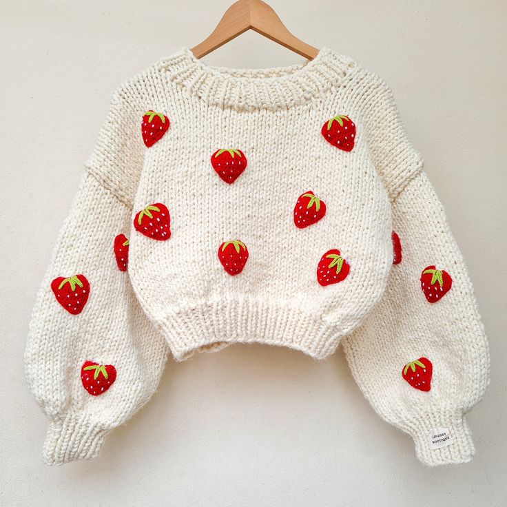 a white sweater with red strawberries on it