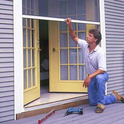 a man is sitting on the porch with his hand up in front of an open door