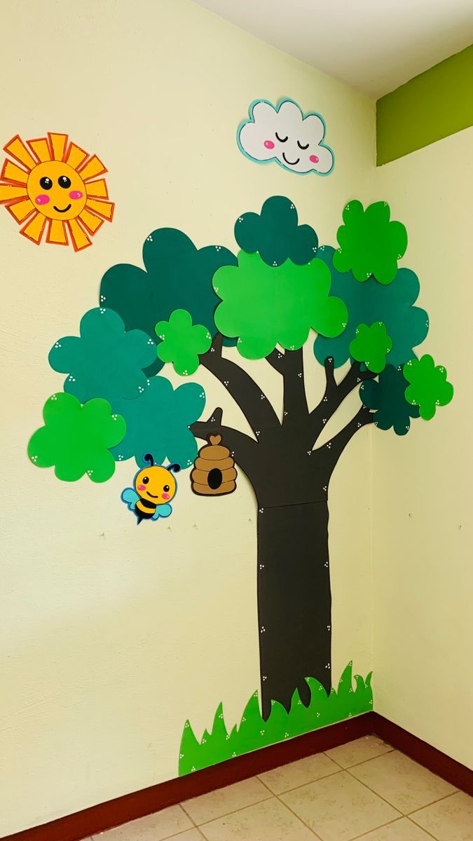 a tree with some animals hanging from it's branches in front of a wall