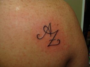 a person with a tattoo on their back has the letter z in cursive writing