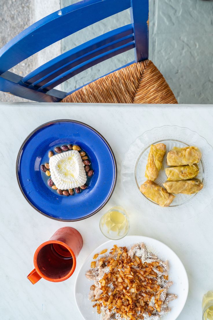 a white table topped with plates and bowls filled with food next to glasses of wine