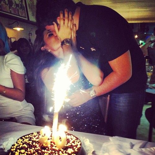 a man and woman kissing in front of a birthday cake with sparklers on it