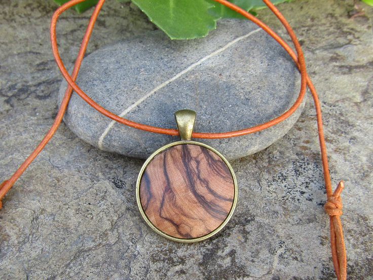 "Lovely bronze pendant medallion with a handmade cabochon Ø 25 mm - 0.98 inches in fine olive wood with a 75 cm - 29.5 inches long bronze plated chain or an adjustable leather cord 1 meter ( 39.37 \" ) naturally the grain of the olive wood can vary from item to item , but in any case you will get a pendant with an olive wood cabochon with beautiful grain handcrafted by us in Portugal the olive wood is finely sanded and oiled with olive oil" Brown Medallion Amulet Necklace, Brown Amulet Style Round Pendant Necklace, Brown Amulet Style Necklace With Round Pendant, Brown Amulet Necklace With Round Pendant, Bohemian Natural Wood Necklaces As Gift, Bohemian Natural Wood Necklace As Gift, Brown Engraved Brass Jewelry, Brown Necklace With Large Round Pendant, Handmade Natural Wood Pendant Jewelry