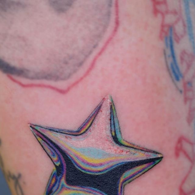 a close up of a person's arm with a star tattoo on it