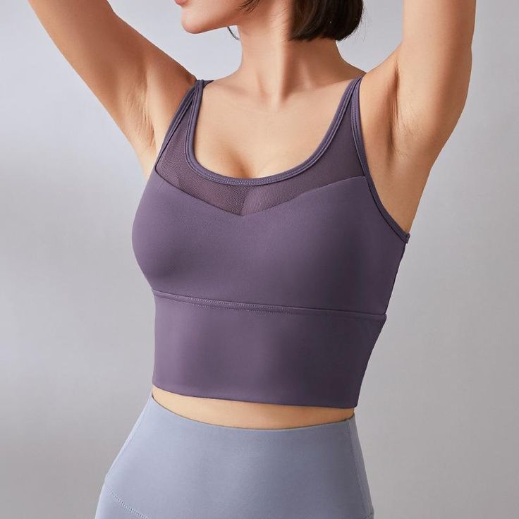 a woman in grey sports bra top holding her arm up to her head with both hands