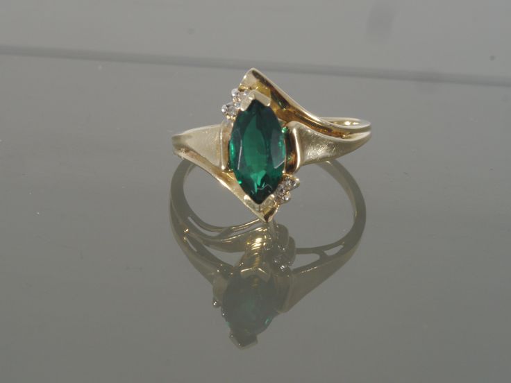 This is a gorgeous bypass ring crafted from 14k yellow gold that features one synthetic marquise chrome diopside accented with two tiny round faceted diamonds on each side. This ring would make a great engagement, promise, anniversary, or right-hand ring. This ring will be shipped in a brand new gift box. RING SIZE: 7.0 (Sizable by your local jeweler) Metal: 14k yellow gold (Verified by acid test) Gemstone: 1 Marquise Synthetic Chrome Diopside (approx. 10.0mm x 5.0mm) & 4 round faceted diamo 14k Gold Marquise May Birthstone Jewelry, Yellow Gold Emerald Jewelry With Marquise Cut, Marquise Cut Emerald Jewelry In Yellow Gold, Formal Green Marquise Jewelry, Fine Jewelry With Marquise Cut May Birthstone, Green Marquise 14k Gold Jewelry, Green Marquise Ring With Diamond Accents, Marquise Emerald Ring For Formal Occasions In May, Green Marquise Rings With Diamond Accents