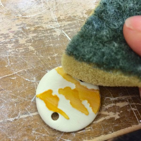 a person holding a piece of bread with yellow paint on it next to a button