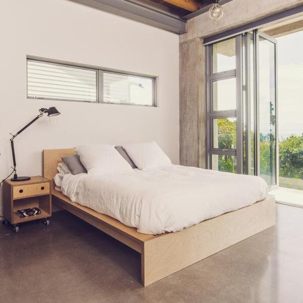 a bed with white sheets and pillows in a bedroom next to a sliding glass door