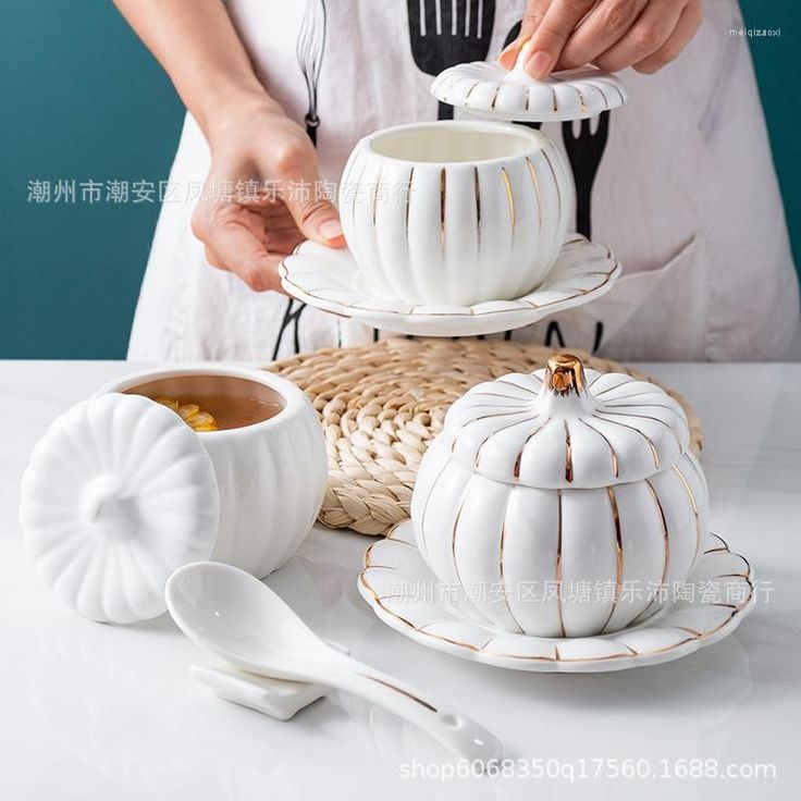 a person pouring tea into a cup and saucer on a table with other items