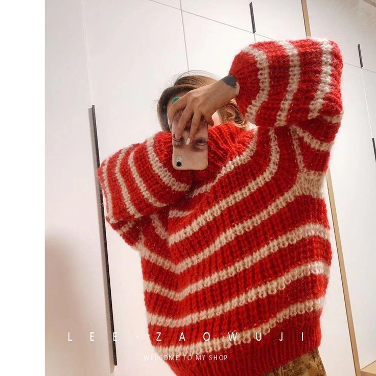 a woman taking a selfie in front of a mirror wearing a red and white striped sweater