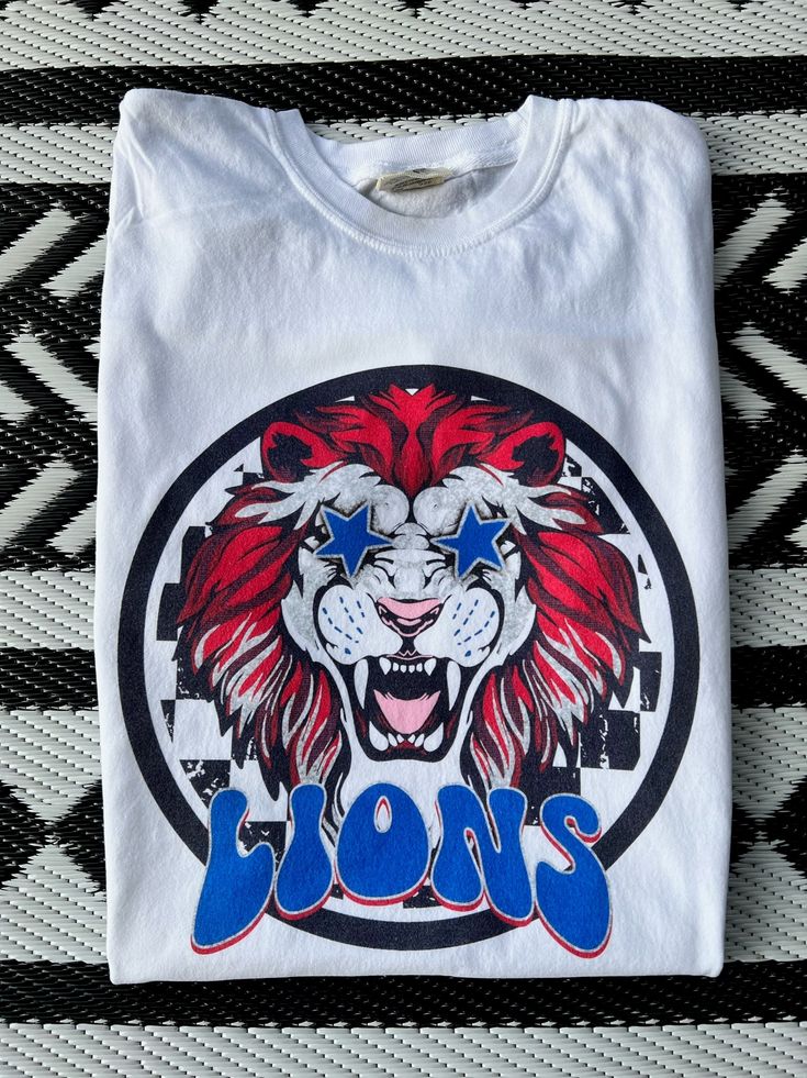 Get this popular new Lions Mascot shirt and show off your school spirit in style!  Each shirt is printed in-house by me using high-quality materials on a Comfort Colors shirt, known for its exceptional comfort, style, and durability. Even the glitter is printed! No need to worry about peeling glitter vinyl, or messy glitter flakes. Available in unisex sizes S to 3X, and youth sizes, we've got you covered regardless of your preferred fit. The Preppy Lions Shirt features a classic crew neck and sh School Spirit T-shirt With Graphic Print, Custom Print School Spirit Tops For Fan Gear, School Spirit Shirt With Screen Print For Game Day, School Spirit Fan Gear Tops With Custom Print, School Spirit Tops With Custom Print For Fan Gear, White Custom Print T-shirt For Fan Gear, White Collegiate Shirt For Fan Merchandise, School Spirit Game Day Shirt With Screen Print, Custom Print Tops For School Spirit Fan Gear