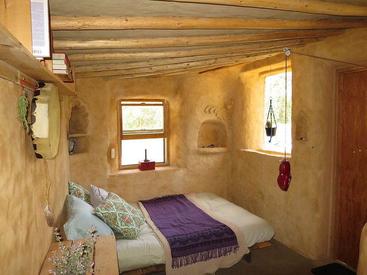 a bed sitting in a bedroom next to two windows