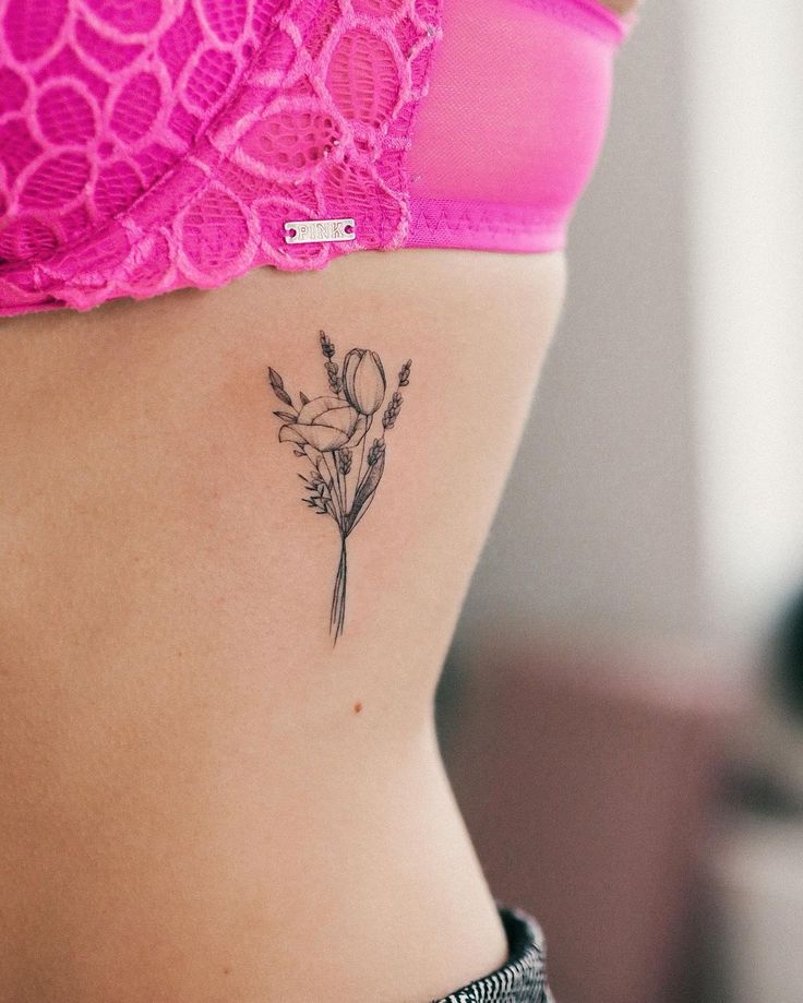 a woman's stomach with a flower tattoo on her lower side ribcage