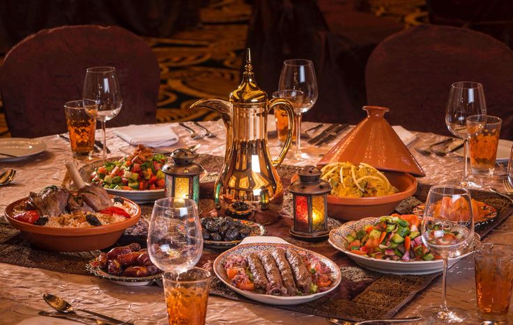 a table topped with lots of plates and bowls filled with different types of food next to wine glasses