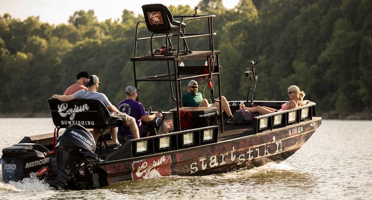 a group of people riding on the back of a motor boat in water with trees behind them