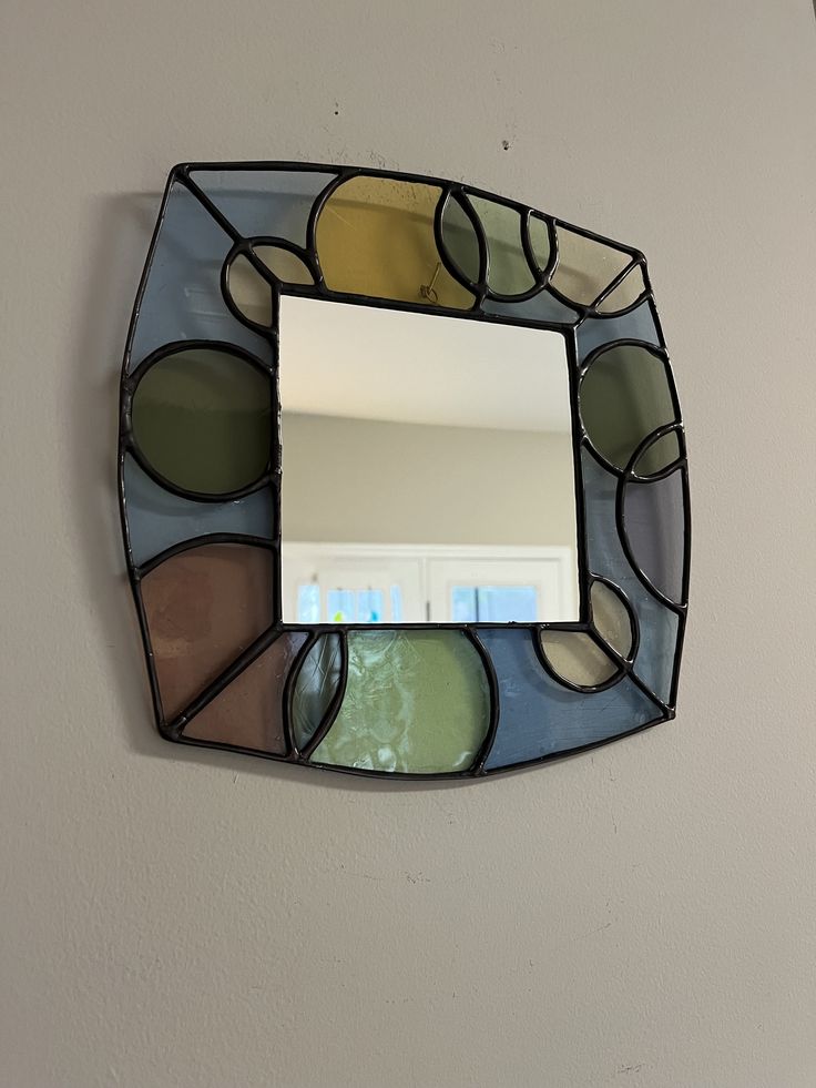 a mirror mounted to the side of a wall next to a white wall with an oval design on it