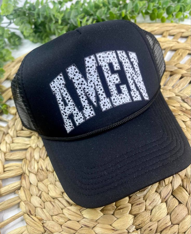 This all black trucker has has a mesh back, 100% polyester foam front, structured five-panels, mid-profile, pre-curved visor with braid detailing and a super cute black & white speckled "AMEN" message. Black Breathable Hats For Spring, Spring Black Breathable Hat, Black Breathable Baseball Cap For Spring, Breathable Black Baseball Cap For Spring, Mesh Trucker Hat With Curved Visor For Baseball, Mesh Baseball Cap With Letter Print And Curved Brim, Trendy Black Breathable Baseball Cap, Trendy Breathable Black Baseball Cap, Adjustable Mesh Back Snapback Hat For Summer