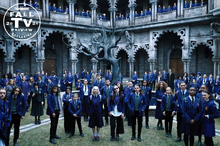 a large group of people standing in front of a building with blue coats and ties