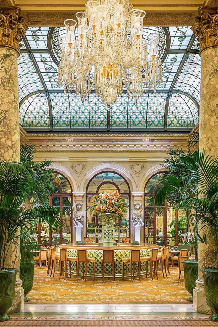 an ornate dining room with chandelier and large potted plants in the center