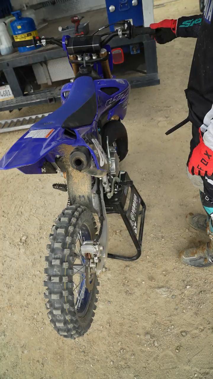 a blue dirt bike parked on top of a dirt field