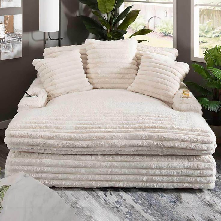 a large pile of white pillows sitting on top of a couch