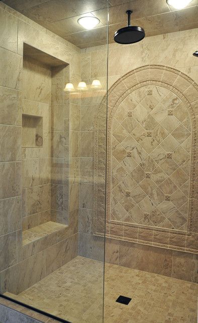 a walk in shower sitting next to a tiled wall and floor with two lights on it