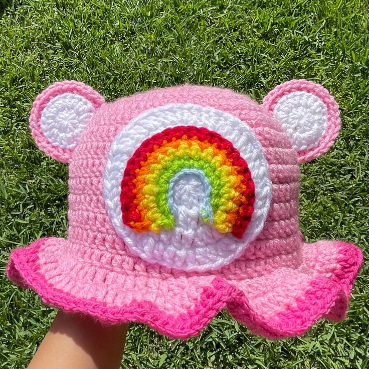 a pink crocheted hat with a rainbow on it and a white bear in the center