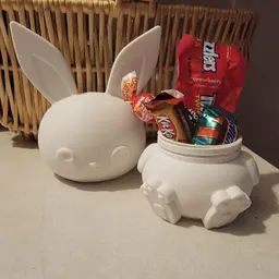 a basket with some candy in it next to a white bunny shaped jar filled with candy