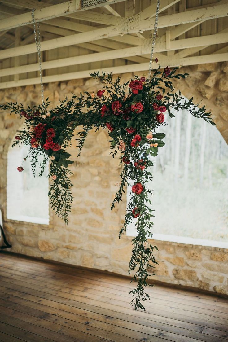 flowers and greenery are hanging from the ceiling in an old stone building with wood flooring