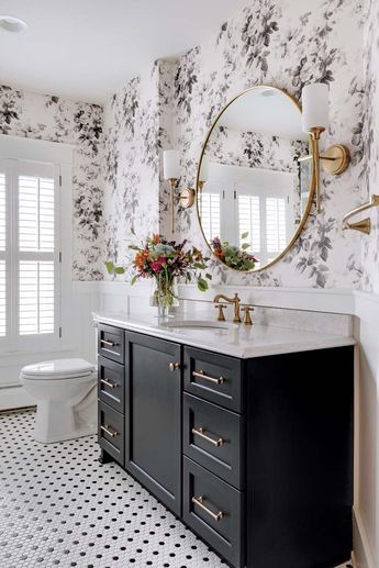 a bathroom with black and white wallpaper, gold accents and a round mirror above the sink