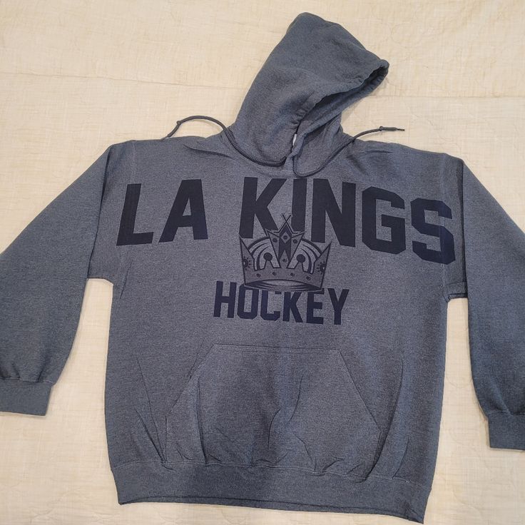 a hooded sweatshirt with the la kings hockey logo is laying on a white sheeted surface