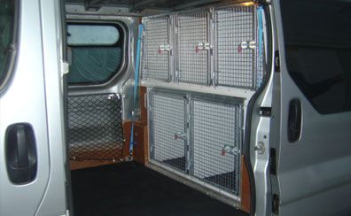 the inside of a van with its doors open and several metal cages in it's back