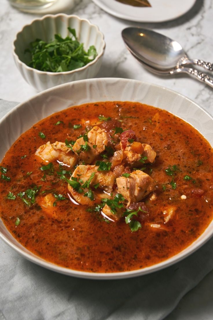 a white bowl filled with soup and garnished with parsley on the side