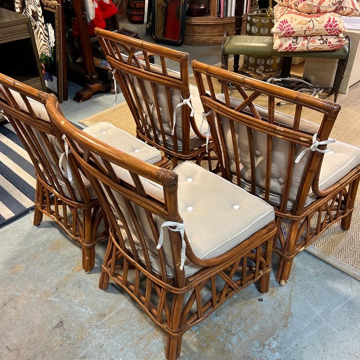 four bamboo chairs with white cushions in a store