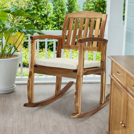 a wooden rocking chair sitting on top of a porch next to a potted plant