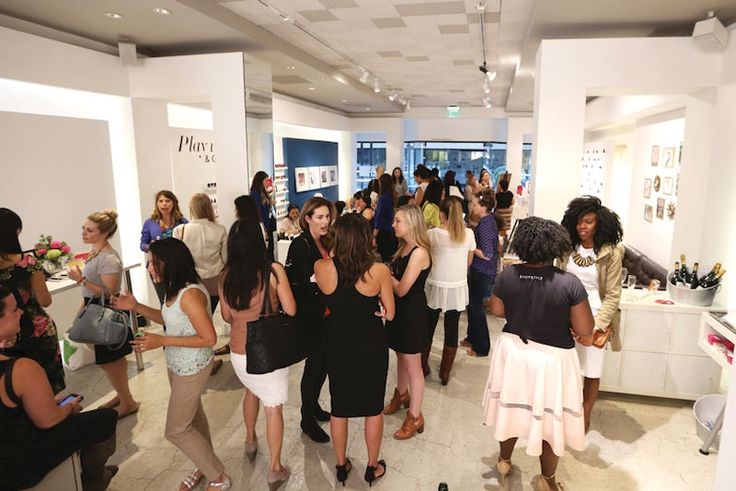 a group of people standing around in a room with white walls and ceilings, all looking at items on display