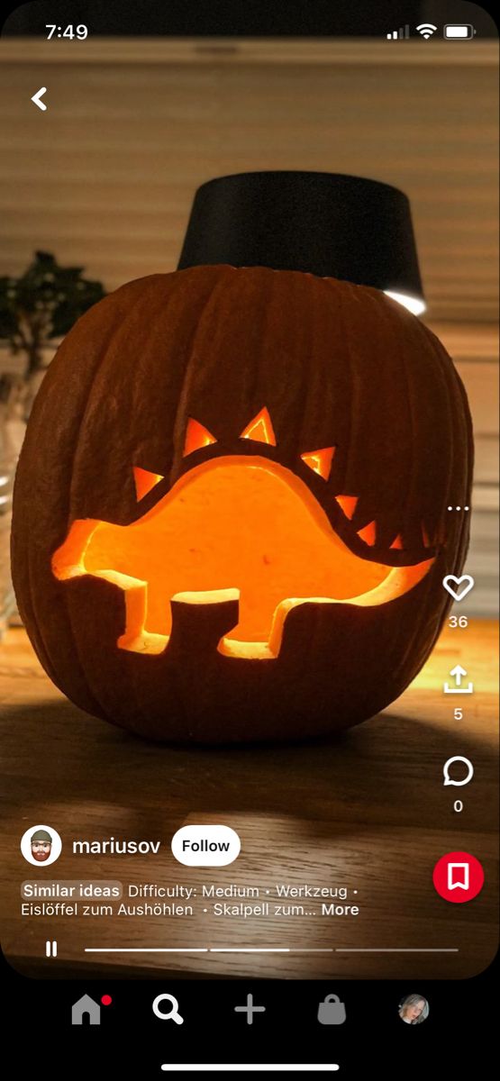 a pumpkin carved to look like a dinosaur with its mouth open and teeth wide open