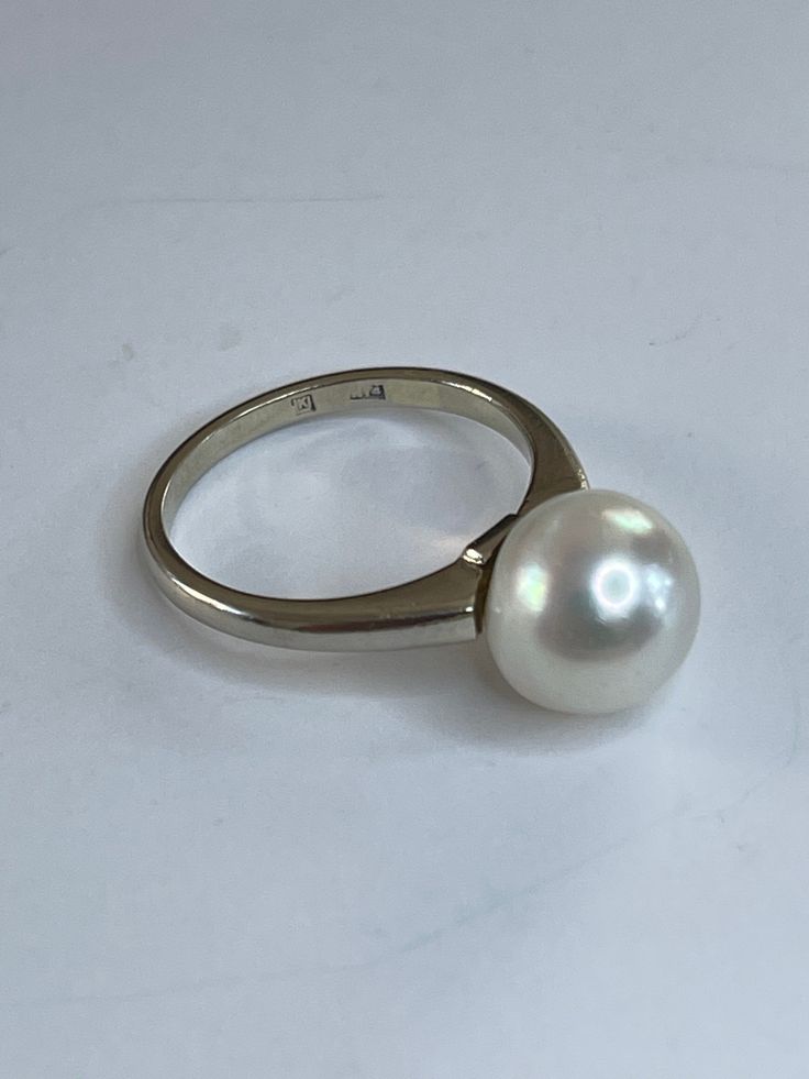 . This pearl is lovely. It's luster is so high you can see your reflection. It's a nice white color with just the slightest hint of pink. The 14k white gold mounting is clean simple lines that really show off the pearl. The band is 2mm at the pearl and 1.5mm wide at the back. I've cleaned with only dawn dish soap and a toothbrush. 10mm cultured Pearl 3.62 grams 14k and pearl Size 6 3/4 White Akoya Pearl Timeless Ring, Timeless White Akoya Pearl Ring, White Pearl Drop Ring For Formal Occasions, Classic White Pearl Ring With Drop Detail, Classic White Pearl Ring, Formal Minimalist Pearl Ring With Polished Finish, Classic Round Pearl Ring With Pearl Drop, Classic Pearl White Rings With Pearl Drop, Classic Pearl Ring With Pearl Drop