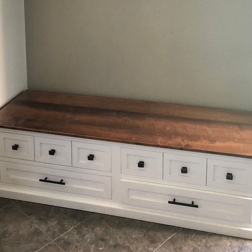 a white bench with wooden top and drawers