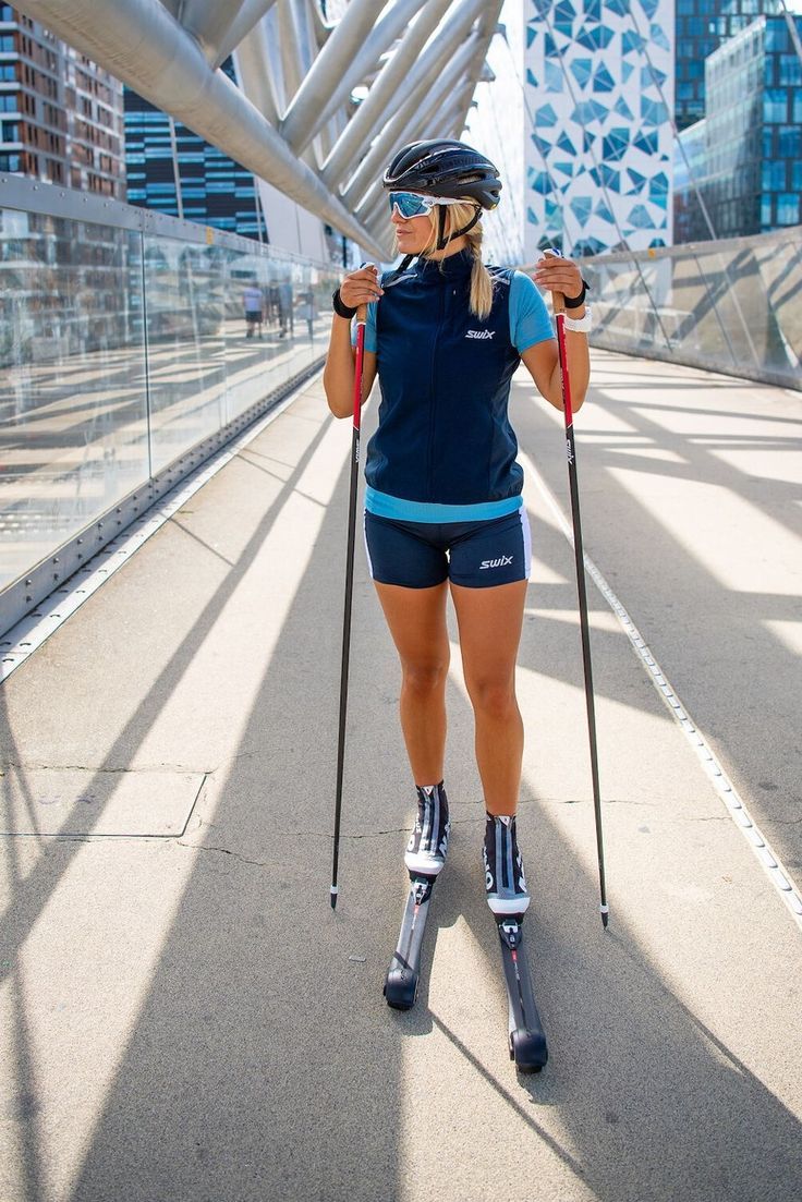 a woman with skis and poles on a bridge in front of a cityscape