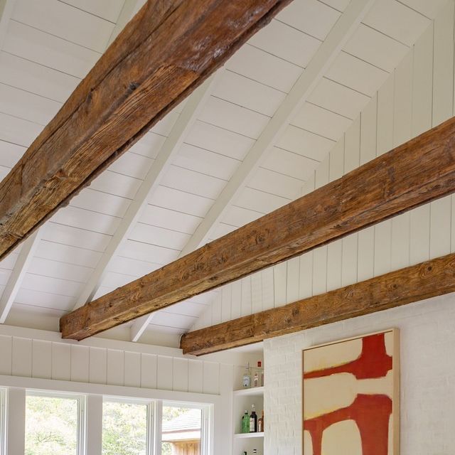 a living room with white walls and wooden beams on the ceiling is filled with furniture