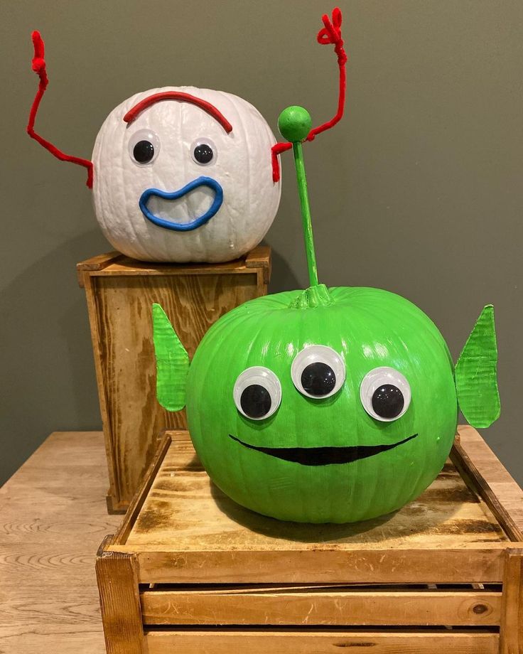 two pumpkins with faces painted on them sitting on top of a wooden box next to each other