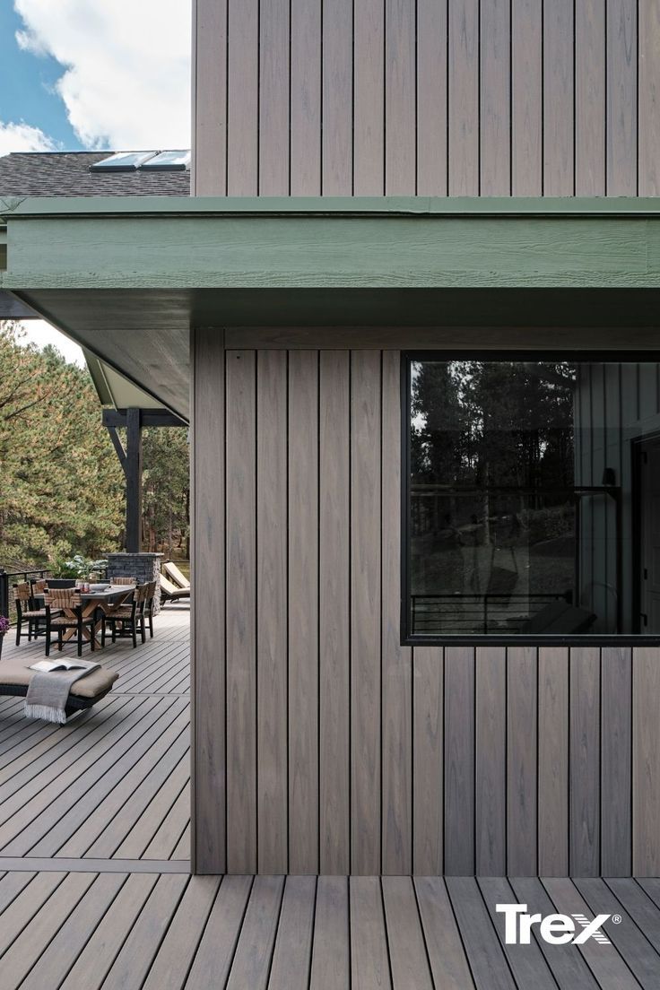 a wooden deck with chairs and tables next to a large window that reads trex