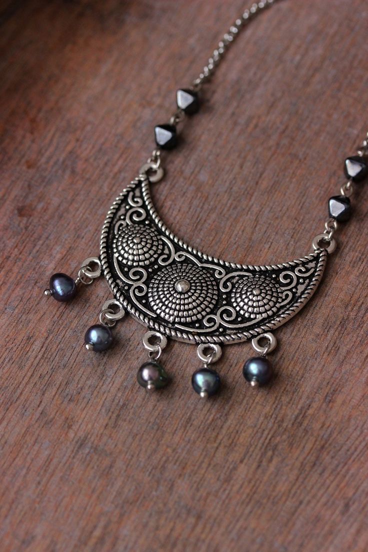 Beautiful boho necklace with dark freshwater irregular shape pearl beads, black-gray bicone shape czech glass beads, antique silver tone ethnic style semicircle pendant (base: jewellry metal alloy) and stainless steel chain with steel lobster claw. The chain is from lead free & nickel free metal. Perfect for everyday wear and an unique gift! The length of necklace is 48.5 cm or about 19.1 inches. Other necklaces of my shop you can see here: https://www.etsy.com/shop/NaTavelli?section_id=14843046 Bohemian Metal Beaded Necklace With Black Beads, Antique Silver Beaded Bohemian Jewelry, Bohemian Silver Necklaces With Polished Beads, Bohemian Silver Necklace With Polished Beads, Bohemian Silver Jewelry With Black Beads, Silver Bohemian Necklaces With Round Beads, Artisan Silver Beaded Necklace Nickel Free, Bohemian Pearl Necklace With Polished Beads, Silver Bohemian Pearl Necklace With Beads