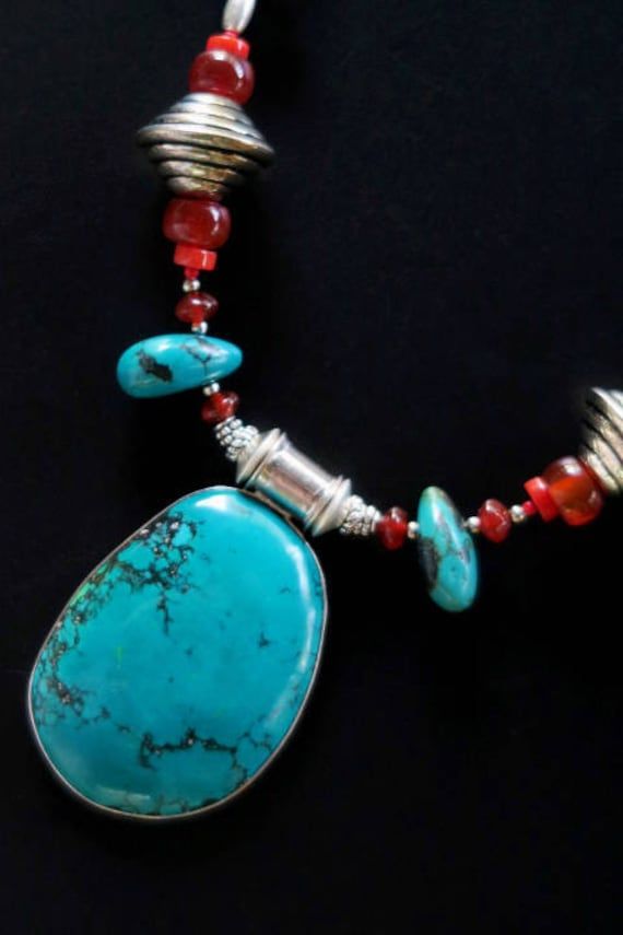 This beautiful long necklace was handcrafted with a large natural-turquoise pendant from Nepal. MEASUREMENTS (1 inch = 2.54 cm): Pendant Size = 2-1/4 inches long x 1-/3/8 inches wide x 3/8 inch deep Necklace Length = 20 inches (neckline circumference) Weight = 2.4 oz Shipping weight = 8 oz TM Image Library 9-21-2017 More turquoise, carnelians, coral, and Baltic-amber extend up the sides, complementing the large turquoise pendant in the center. It has a lobster-claw clasp at the back for a secure Unique Turquoise Long Necklace, Artisan Turquoise Necklace With Rectangular Pendant, Artisan Turquoise Pendant Necklace For Healing, Turquoise Amulet Pendant Necklace With Natural Stones, Turquoise Square Pendant Necklace For Jewelry Making, Artisan Long Turquoise Necklace Gift, Bohemian Turquoise Necklace With Large Stone, Bohemian Blue Necklace With Rectangular Pendant, Bohemian Blue Rectangular Pendant Necklace