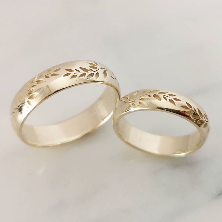 two gold wedding bands with leaves on them