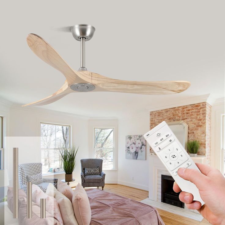 a person holding a remote control in front of a ceiling fan