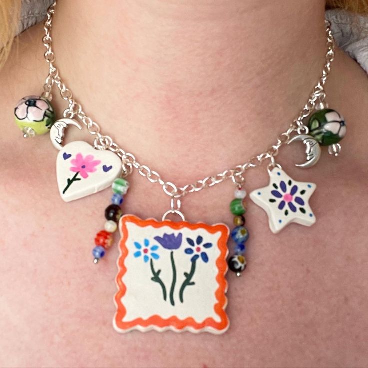 a close up of a woman wearing a necklace with flowers and stars on the front