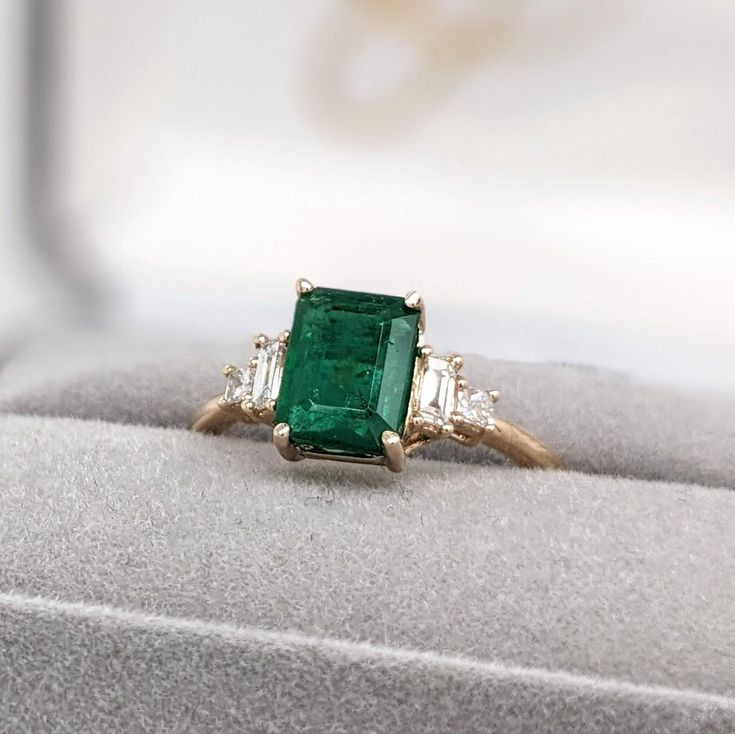 A vivid green emerald looks exquisite in this elegant minimalist ring with cute diamond accents. A statement ring design perfect for an eye catching engagement or anniversary. This ring also makes a beautiful May birthstone ring for your loved ones. This ring is made with solid 14K Gold and natural Earth mined SI / G-H diamonds. If you're interested in purchasing this setting with a different center stone please message us! May Birthstone Rings, Designer Silver Jewellery, Jewelry Showcases, May Birthstone, Minimalist Ring, Natural Earth, Green Emerald, Minimalist Rings, Earring Findings